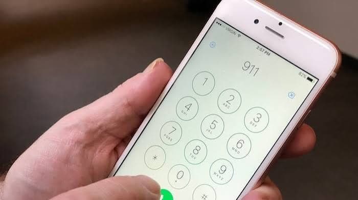 Une main tient un téléphone cellulaire sur lequel le numéro 911 est composé.