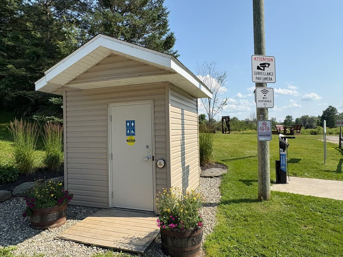 Bloc sanitaire du parc, portant les affiches « Wifi disponible ici » et l'avis de surveillance par caméra