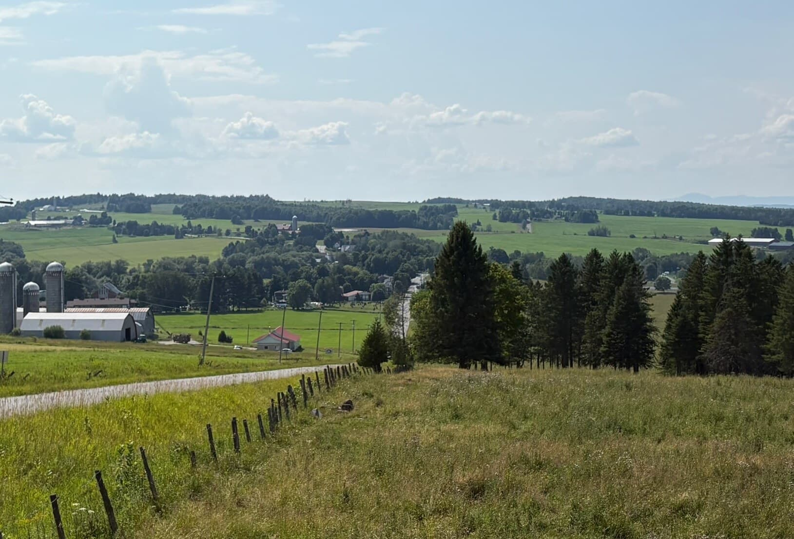 Vue plongeante sur la vallée agricole de Martinville, avec une ferme laitière, ses silos et un clocher au loin